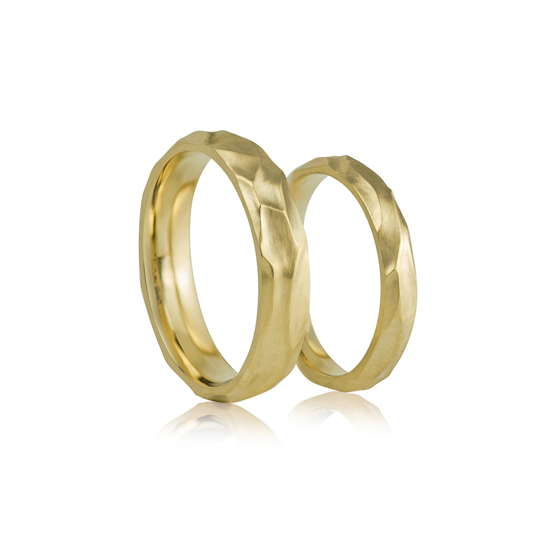 skulpturinis dizainas geltono aukso vestuviniai ziedai porai ant balto fono